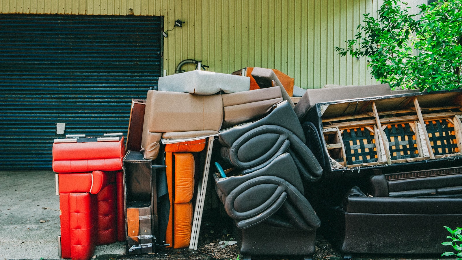 Discarded furniture piled up in front of a garage.